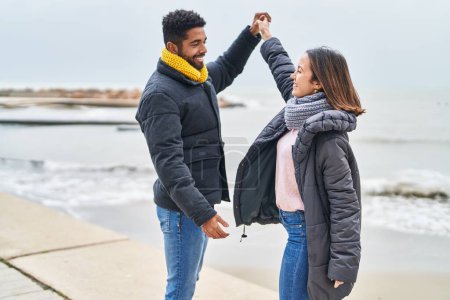 Téléchargez les photos : Couple homme et femme souriant danse confiante au bord de la mer - en image libre de droit