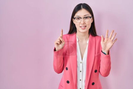 Foto de Chino negocio joven mujer usando gafas mostrando y apuntando hacia arriba con los dedos número seis mientras sonríe confiado y feliz. - Imagen libre de derechos