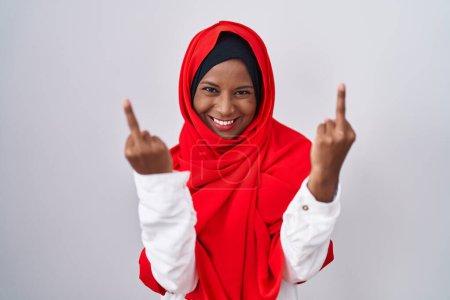 Foto de Young arab woman wearing traditional islamic hijab scarf showing middle finger doing fuck you bad expression, provocation and rude attitude. screaming excited - Imagen libre de derechos
