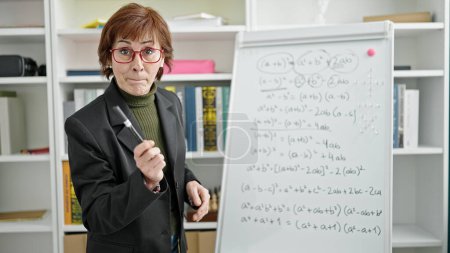 Photo for Mature hispanic woman teacher teaching maths lesson at library university - Royalty Free Image