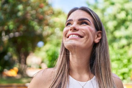 Téléchargez les photos : Young beautiful hispanic woman smiling confident looking to the sky at park - en image libre de droit