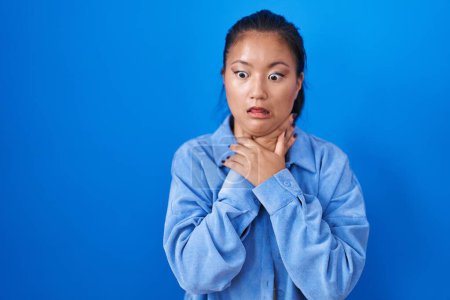 Téléchargez les photos : Asiatique jeune femme debout sur fond bleu criant suffoquer parce étranglement douloureux. problème de santé. concept d'asphyxie et de suicide. - en image libre de droit