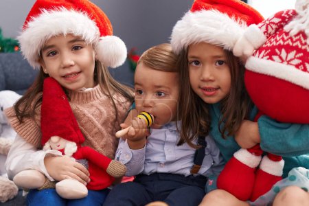 Foto de Grupo de niños abrazándose unos a otros sentados en el sofá por la decoración de Navidad en casa - Imagen libre de derechos