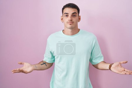 Photo for Handsome hispanic man standing over pink background clueless and confused with open arms, no idea concept. - Royalty Free Image