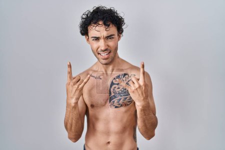 Photo for Hispanic man standing shirtless shouting with crazy expression doing rock symbol with hands up. music star. heavy concept. - Royalty Free Image