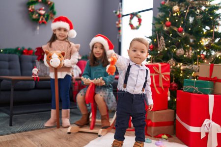 Foto de Grupo de niños jugando con el balanceo de renos y el juguete de caballo por árbol de Navidad en casa - Imagen libre de derechos