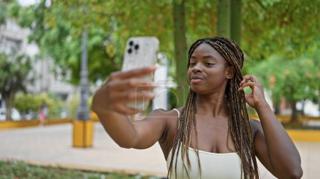 Téléchargez les photos : Femme afro-américaine faire selfie par smartphone souriant au parc - en image libre de droit