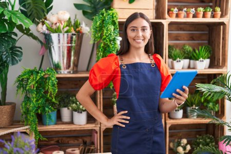 Photo for Young beautiful hispanic woman florist smiling confident using touchpad at florist - Royalty Free Image