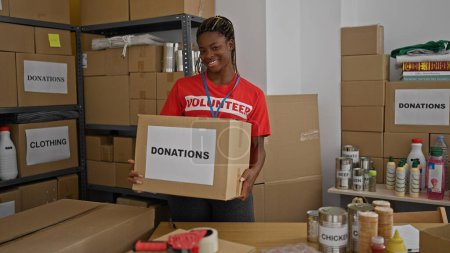 Photo for African american woman volunteer smiling confident holding donations package at office - Royalty Free Image