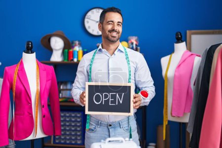 Photo for Hispanic man with beard working as dressmaker at atelier winking looking at the camera with sexy expression, cheerful and happy face. - Royalty Free Image