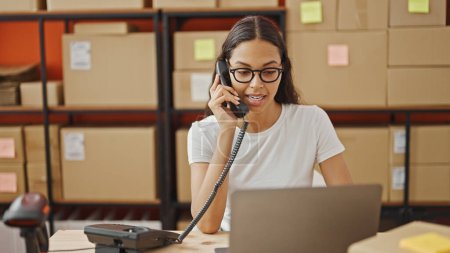 Téléchargez les photos : Femme afro-américaine commerce électronique travailleur d'affaires parlant au téléphone à l'aide d'un ordinateur portable au bureau - en image libre de droit