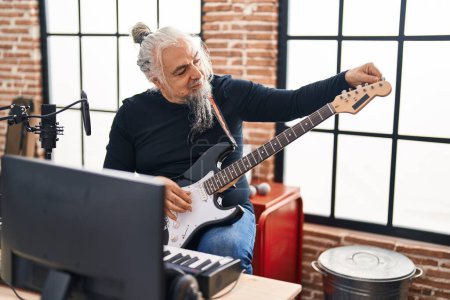 Téléchargez les photos : Moyen Age homme aux cheveux gris musicien souriant confiant jouer de la guitare électrique au studio de musique - en image libre de droit