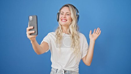 Photo for Young blonde woman smiling confident having video call over isolated blue background - Royalty Free Image
