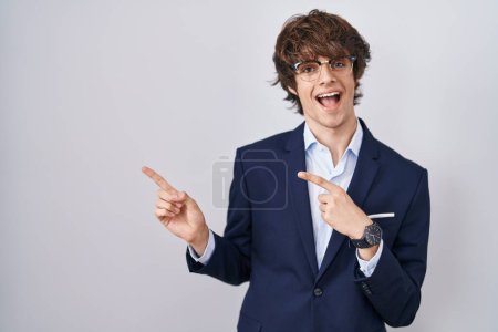 Photo for Hispanic business young man wearing glasses smiling and looking at the camera pointing with two hands and fingers to the side. - Royalty Free Image