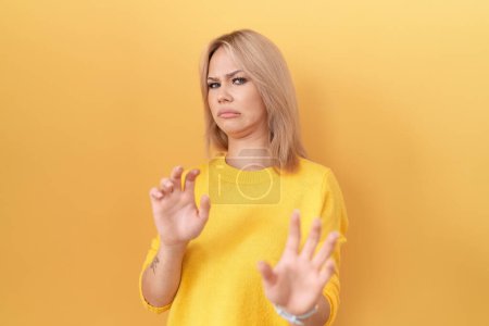 Téléchargez les photos : Jeune femme caucasienne portant un pull jaune expression dégoûtée, mécontente et craintive faisant visage dégoûtant parce que réaction d'aversion. - en image libre de droit