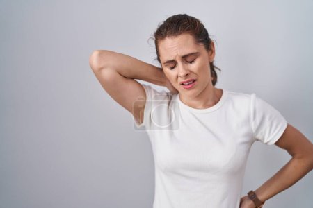 Téléchargez les photos : Belle femme brune debout sur un fond isolé souffrant d'une blessure au cou, toucher le cou avec la main, douleur musculaire - en image libre de droit