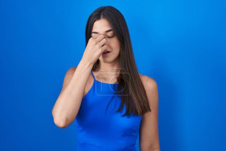 Téléchargez les photos : Femme hispanique debout sur fond bleu fatigué se frottant le nez et les yeux ressentant fatigue et maux de tête. concept de stress et de frustration. - en image libre de droit