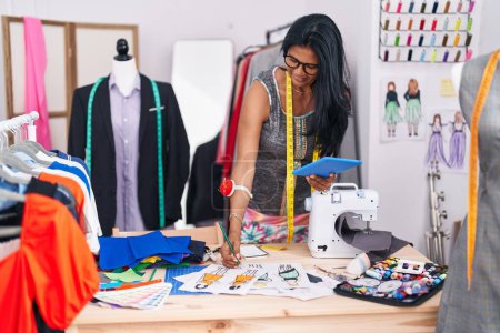 Téléchargez les photos : Femme hispanique du Moyen Age tailleur en utilisant la conception de vêtements de dessin tactile au magasin de tailleur - en image libre de droit