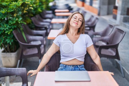 Photo for Young blonde woman stretching arms sitting on chair at coffee terrace - Royalty Free Image