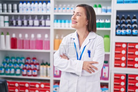 Photo for Middle age woman pharmacist smiling confident standing with arms crossed gesture at pharmacy - Royalty Free Image
