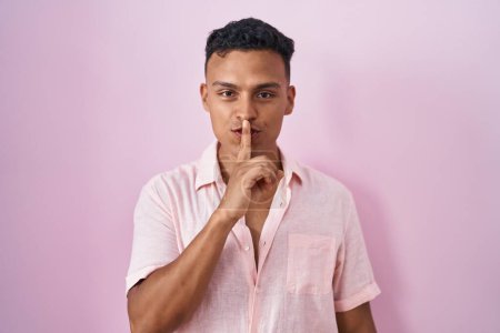 Photo for Young hispanic man standing over pink background asking to be quiet with finger on lips. silence and secret concept. - Royalty Free Image