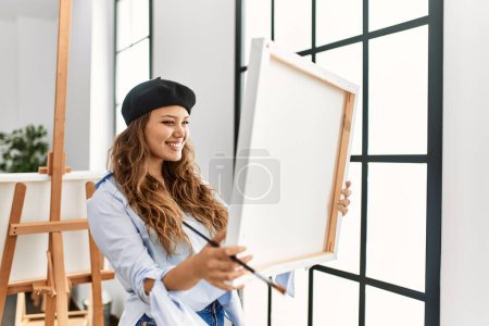 Téléchargez les photos : Jeune belle hispanique femme artiste souriant confiant regarder dessiner à l'atelier d'art - en image libre de droit