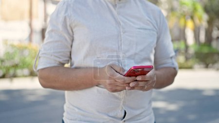 Téléchargez les photos : Young hispanic man using smartphone at park - en image libre de droit