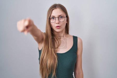 Photo for Young caucasian woman standing over white background pointing with finger surprised ahead, open mouth amazed expression, something on the front - Royalty Free Image