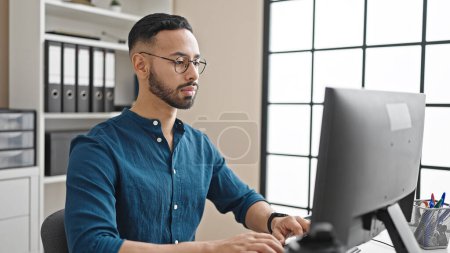 Photo for Young hispanic man business worker using computer with serious face at the office - Royalty Free Image