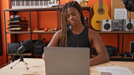 Téléchargez les photos : Musicienne afro-américaine utilisant un ordinateur portable au studio de musique - en image libre de droit