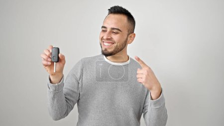 Photo for Hispanic man smiling confident pointing to key of new car over isolated white background - Royalty Free Image