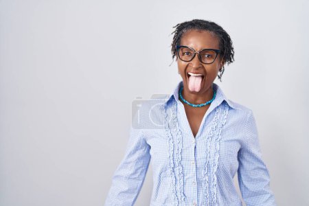 Téléchargez les photos : Femme africaine avec dreadlocks debout sur fond blanc portant des lunettes collant la langue heureux avec une expression drôle. concept d'émotion. - en image libre de droit
