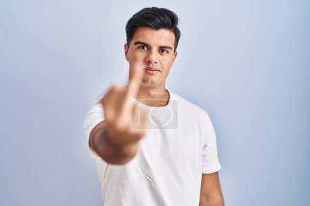 Photo for Hispanic man standing over blue background showing middle finger, impolite and rude fuck off expression - Royalty Free Image
