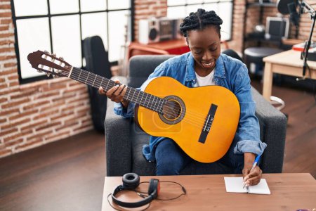 Téléchargez les photos : African american woman musician composing song playing classical guitar at music studio - en image libre de droit