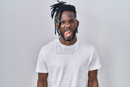 Photo for African man with dreadlocks wearing casual t shirt over white background sticking tongue out happy with funny expression. emotion concept. - Royalty Free Image