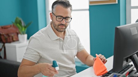 Foto de Hombre de pelo gris trabajador de negocios de limpieza de la mesa y el ordenador en la oficina - Imagen libre de derechos