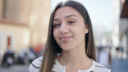 Téléchargez les photos : Jeune belle femme hispanique souriant confiance debout à la rue - en image libre de droit