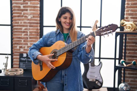 Téléchargez les photos : Jeune musicienne hispanique jouant de la guitare classique au studio de musique - en image libre de droit
