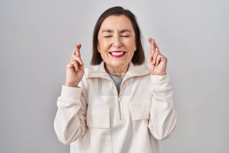 Photo for Middle age hispanic woman standing over isolated background gesturing finger crossed smiling with hope and eyes closed. luck and superstitious concept. - Royalty Free Image