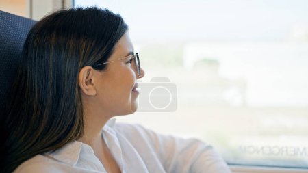 Photo for Young beautiful hispanic woman smiling happy looking through the window inside train wagon - Royalty Free Image