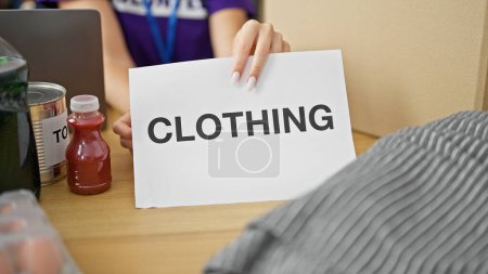 Téléchargez les photos : Jeune femme blonde emballage volontaire paquet de vêtements pour faire un don au centre de charité - en image libre de droit