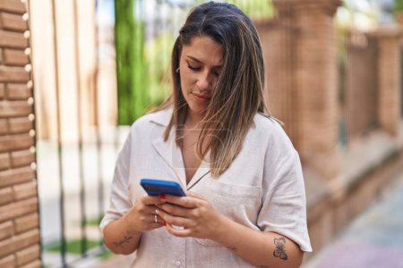 Photo for Young hispanic woman using smartphone at street - Royalty Free Image