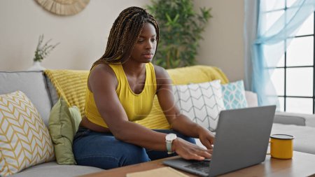 Foto de African american woman using laptop sitting on sofa at home - Imagen libre de derechos