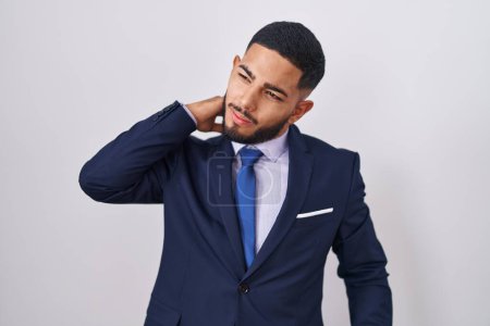 Photo for Young hispanic man wearing business suit and tie suffering of neck ache injury, touching neck with hand, muscular pain - Royalty Free Image