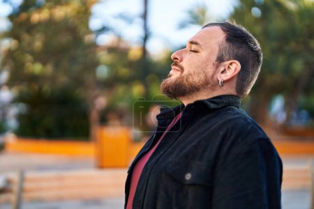 Téléchargez les photos : Jeune homme hispanique souriant respiration confiante au parc - en image libre de droit