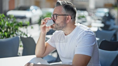 Téléchargez les photos : Homme aux cheveux gris buvant du café assis sur la table à la terrasse du café - en image libre de droit