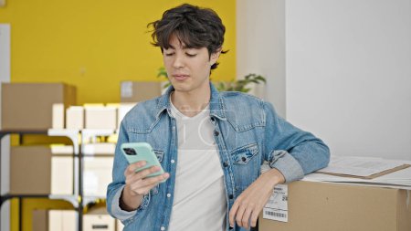 Photo for Young hispanic man ecommerce business worker using smartphone at office - Royalty Free Image