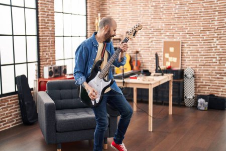 Téléchargez les photos : Jeune musicien chauve jouant de la guitare électrique debout au studio de musique - en image libre de droit