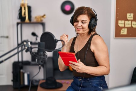 Téléchargez les photos : Femme musicienne d'âge moyen utilisant touchpad chant chanson au studio de musique - en image libre de droit