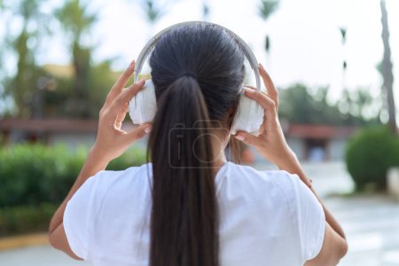 Téléchargez les photos : Jeune femme arabe écoutant de la musique dans la rue - en image libre de droit